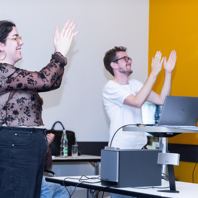 Zwei Workshopleitungen applaudieren. (vergrößerte Bildansicht wird geöffnet)
