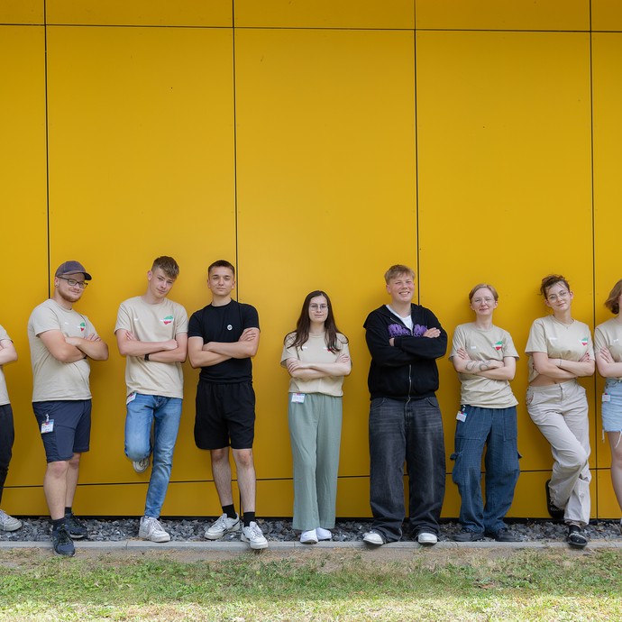 Gruppenfoto von JvJ, die mit gekreuzten Armen vor einer gelben Wand stehen (vergrößerte Bildansicht wird geöffnet)