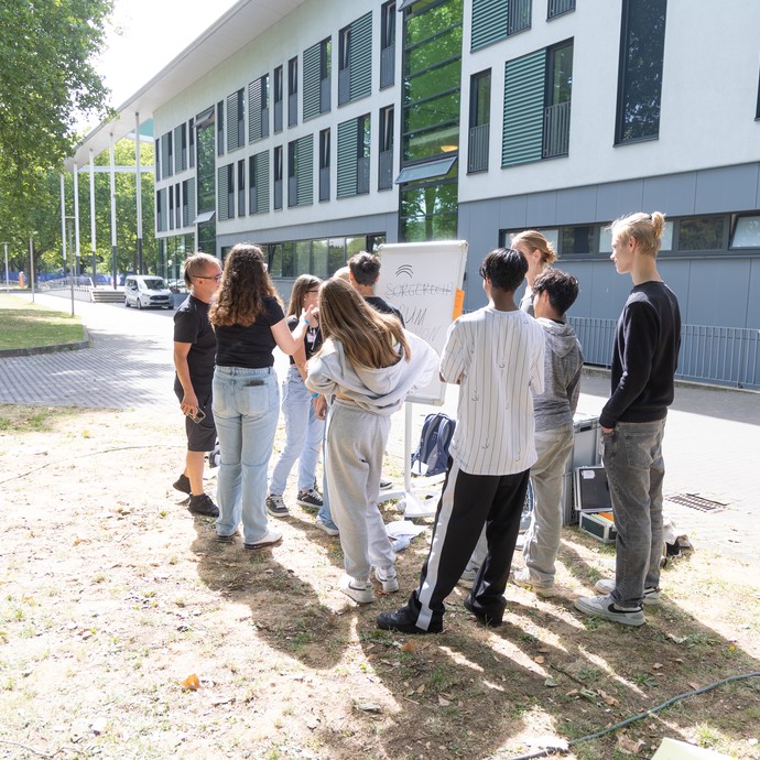 Verschiedene Kinder und Jugendliche draußen bei einem Workshop (vergrößerte Bildansicht wird geöffnet)