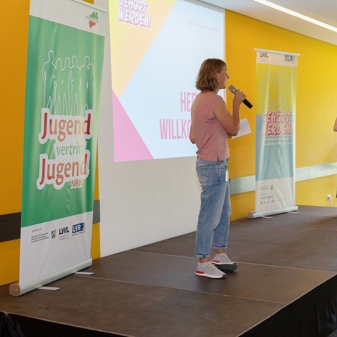 Das Bild zeigt Anna Richters  und Inga Abels, die in ein Mikro spricht, auf der Bühne (vergrößerte Bildansicht wird geöffnet)