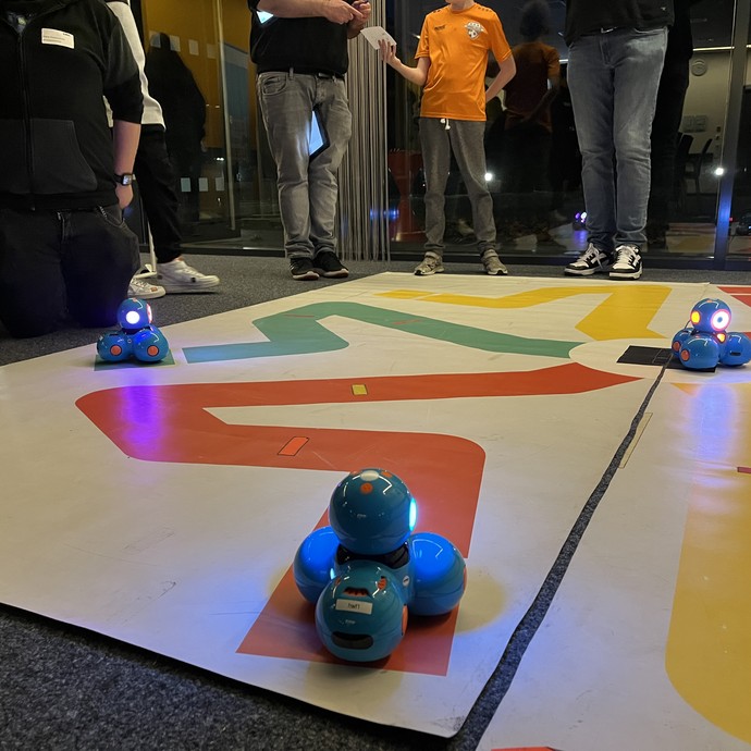 Fachkräfte und junge Menschen testen gemeinsam Dash Roboter. (vergrößerte Bildansicht wird geöffnet)
