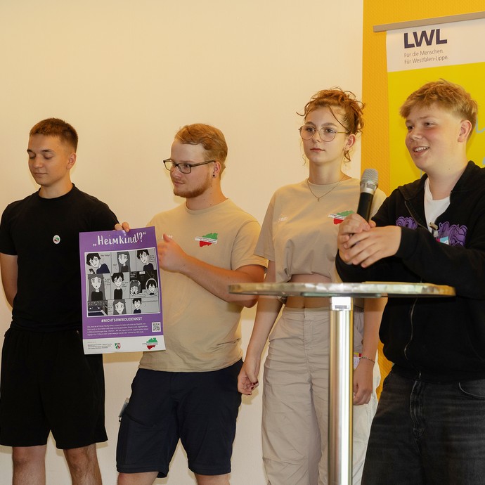 Das Bild zeigt mehrere JvJ-Mitglieder auf der Bühne. Eins hält ein Plakat in der Hand (vergrößerte Bildansicht wird geöffnet)