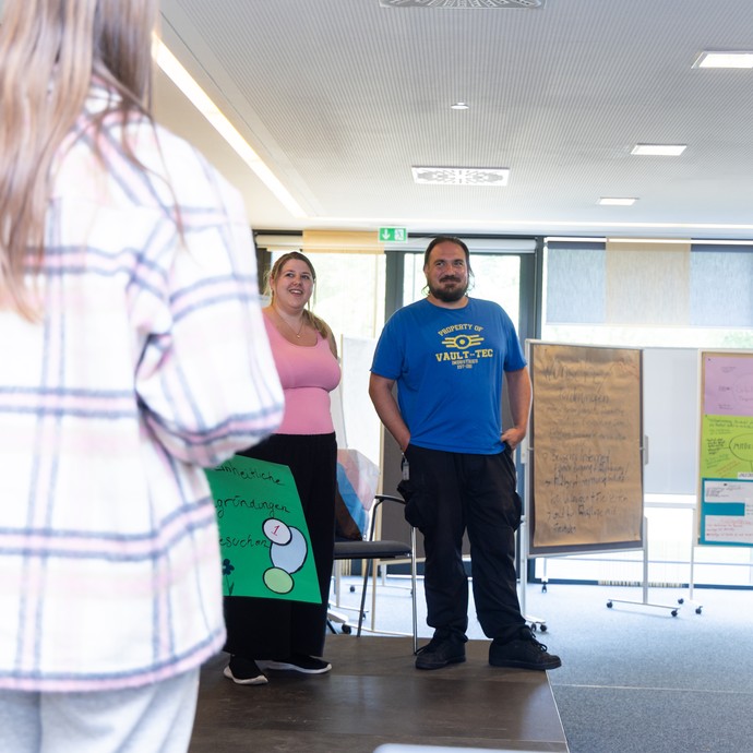 Workshopleitungen und junge Menschen präsentieren auf der Bühne ihre Ergebnisse. (vergrößerte Bildansicht wird geöffnet)