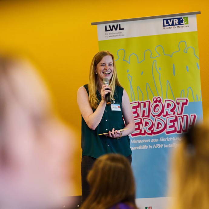 Anna Richters moderiert lachend auf der Bühne. (vergrößerte Bildansicht wird geöffnet)