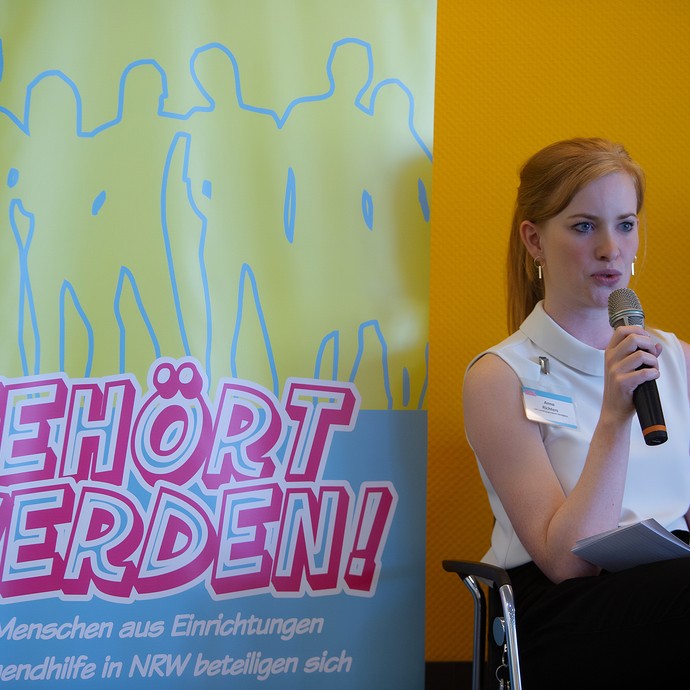 Das Bild zeigt Anna Richters mit Mikro auf der Bühne (vergrößerte Bildansicht wird geöffnet)